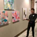 Chris Adams, who runs marketing and events for the Empire Stores building, with artwork on display at Gallery 55. This month’s show is by artists affiliated with Park Slope Windsor Terrace, a Brooklyn-based artist collective. Photo by Mary Frost